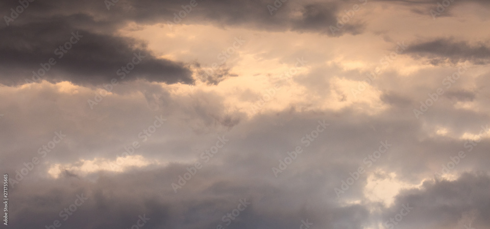 Dramatic dark clouds in a stormy sky during the sunset, a panorama_