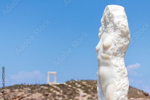 Statue of Ariadne, mythical figure of Greek mythology in Naxos island, Cyclades, Greece. Temple of Apollo ruins (Gate Portara) in the background.