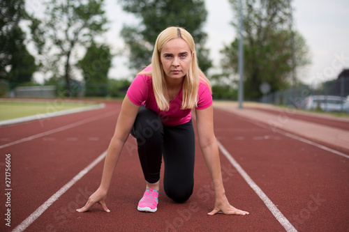 Fit girl practicing stretching exercise at stadium.Beautiful young sports woman doing exercises. A girl is training on a sports field. Young beautiful girl in sports uniform posing on sports field.