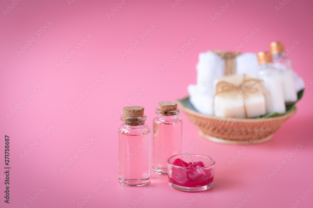 Spa wellness concept with red candle,rose liquid bottle,milk soap,white towels in wooden tray on pink background