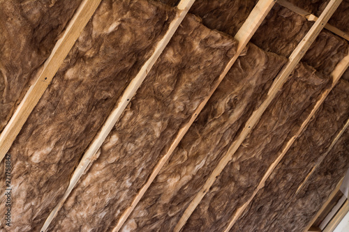 Obraz na plátně Brown glass wool in a wooden frame on a inclined wall near the wooden ceiling in a private house