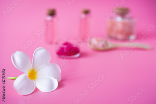 Spa wellness concept white plumeria flower  red candle sea salt  and rose liquid soap bottle on pink background