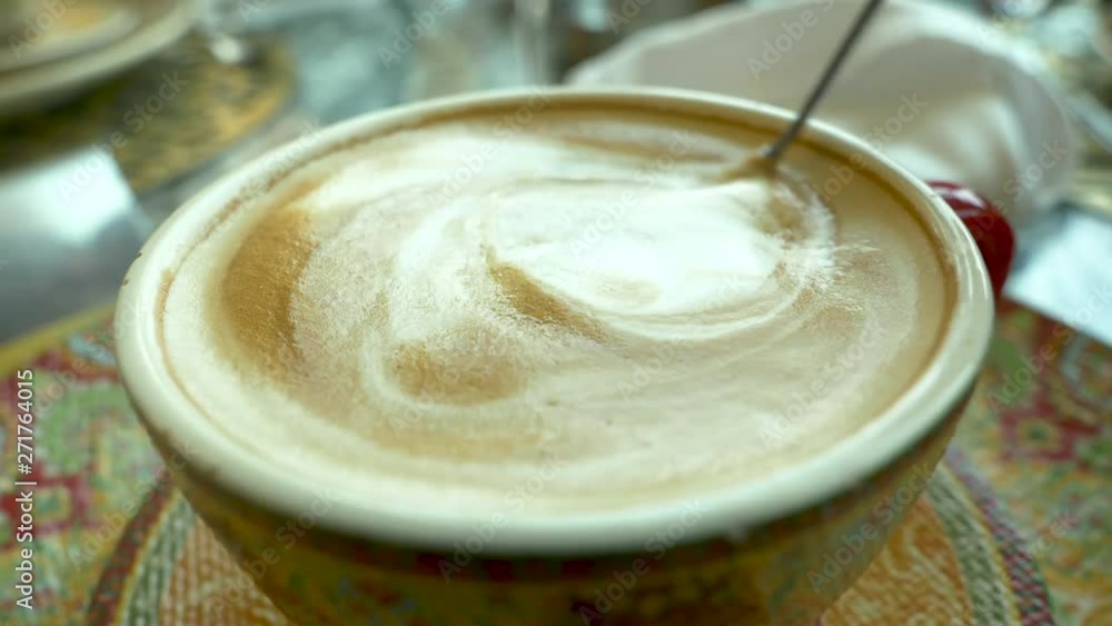 Woman sitting at the table, drinking coffee with cinnamon buns, stiring coffee closeup Woman sitting at the table, drinking coffee with cinnamon buns, stiring coffee closeup