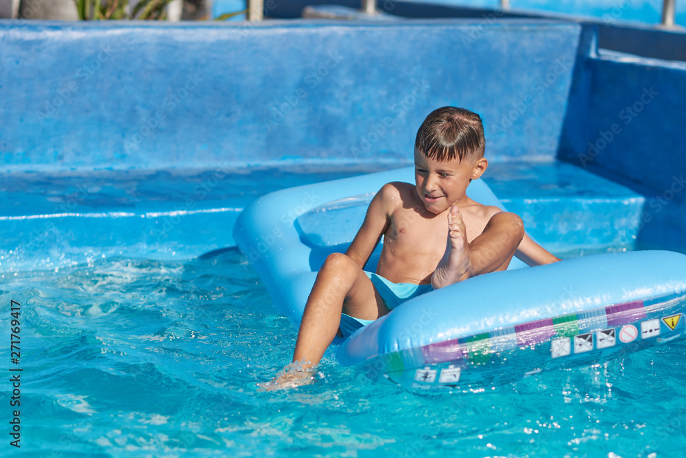 Caucasian boy having fun in swimming pool at resort. He is using inflatable mattress.