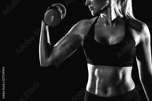Black and white photo of a girl swinging her biceps with a dumbbell.