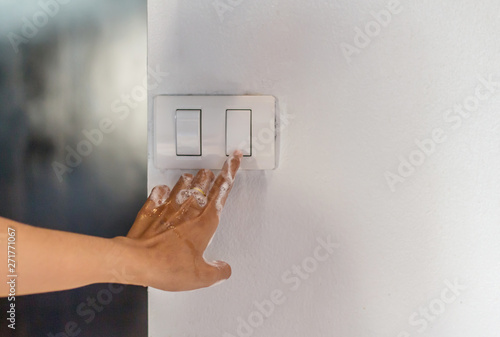Wet hand of women trun on electric switch Concept of do not use electricity with wet hand and safety.