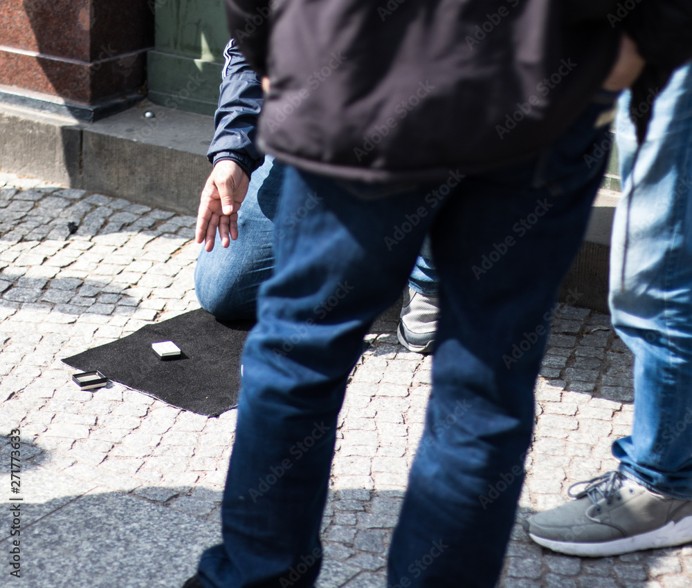 A Shell Game scam being performed on the streets of Germany. A Shell Game scam being performed on the streets of Germany.