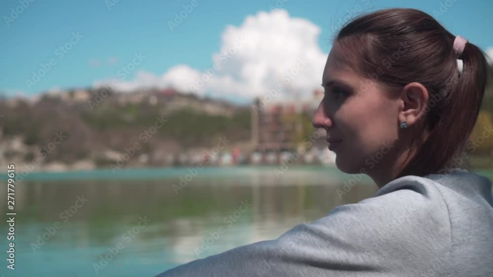 Young woman close-up, sitting by the lake on a spring day, relaxing in nature. Rest, harmony with nature. Young woman close-up, sitting by the lake on a spring day, relaxing in nature. Rest, harmony with nature.