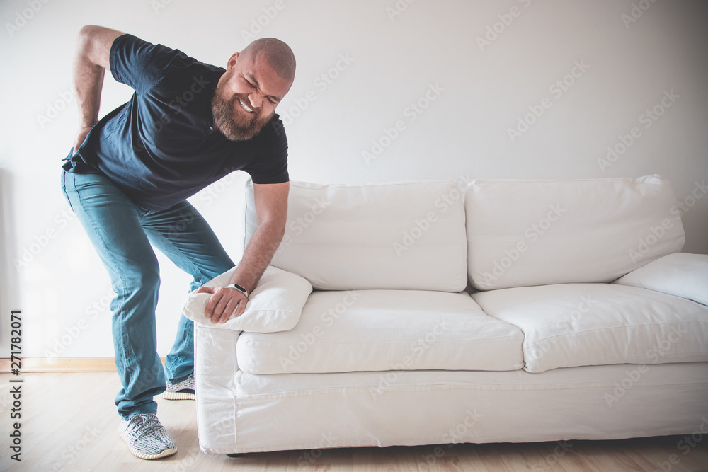 Man having backache (low back pain) while moving or trying to lift a sofa