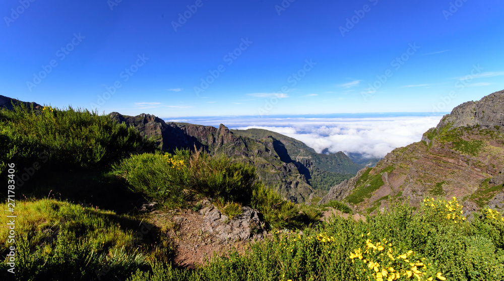 Obraz premium Wide angle shot of Mountain peaks against blue sky with white clouds on a beautiful summer day. Near Pico de Areeiro (Arieiro), Central Madeira, Portugal, Europ