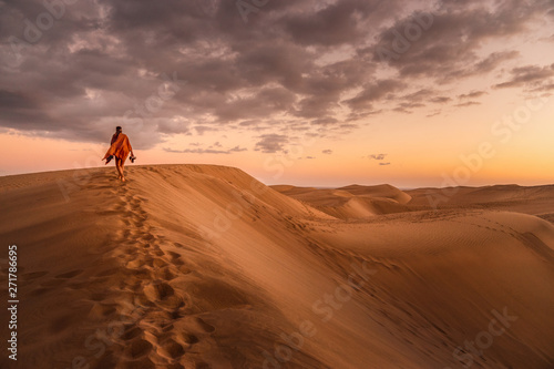 young woman from behind walking in sand dunes of maspalomas  gran canaria