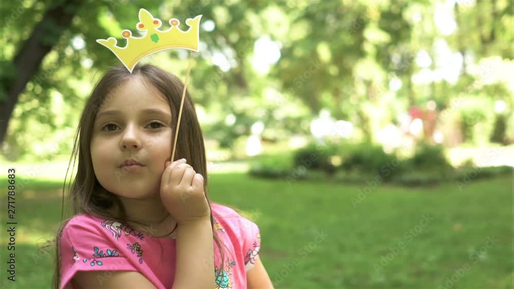 4K. Happy girl child play with paper crown in, city park. Portrait like princess 4K. Happy girl child play with paper crown in, city park. Portrait like princess