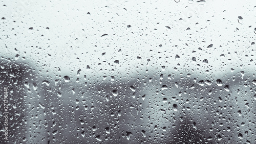 Rainy window. raindrops on a window glass at night. dark blue wet, drops of water rain on glass background. concept of autumn weather. © Natallia