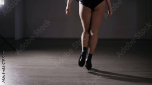 Rare view young sexy woman dressed in mesh tights and black leather underpants .Young girl in black high heels walks by the empty room or fotoshooting studio. Sexy walk in muffled light