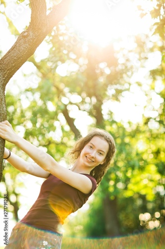 Attractive young girl is posing at tree