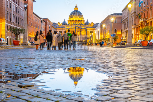 Vatican City by night. Illuminated dome of St Peters Basilica and St Peters Square. Group of tourists on Via della Conciliazione. Rome, Italy photo