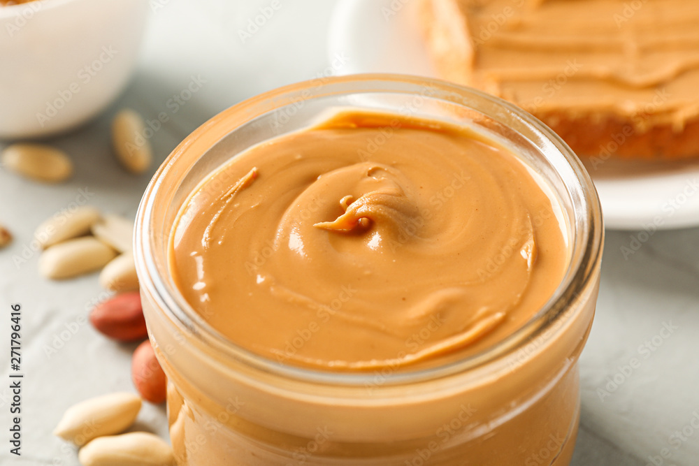 Glass jar with peanut butter, peanut, cup of coffee and peanut butter sandwich on grey background, closeup and space for text Glass jar with peanut butter, peanut, cup of coffee and peanut butter sandwich on grey background, closeup and space for text
