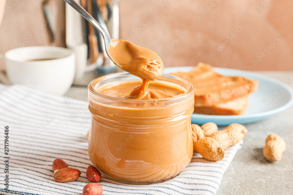 Fototapeta premium Yummy peanut butter breakfast on grey table against light brown background, space for text