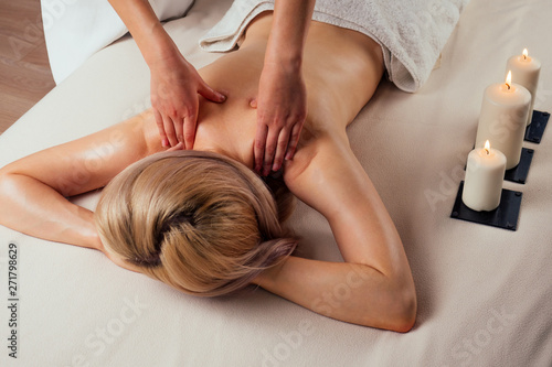 Ayurvedic relaxing.health beauty happy blonde woman in spa salon getting massage .Beautiful girl enjoying day spa resort, lying down on the table treatment procedure next to the candle fire