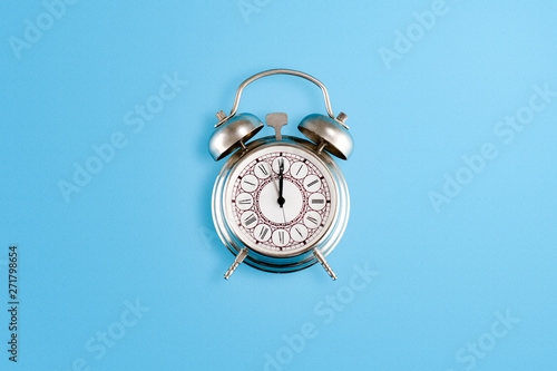 Fotografie Silver old alar clock placed on blue background. Flat lay concept