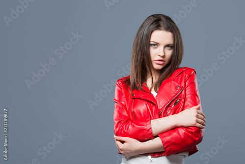 Fashionable style, fashion women's clothing, color combination. Beautiful brunette girl in white dress and red leather jacket isolated gray background