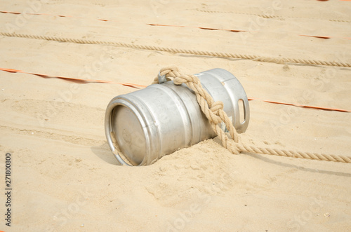 Sports competition with a barrel and a rope on the beach.
