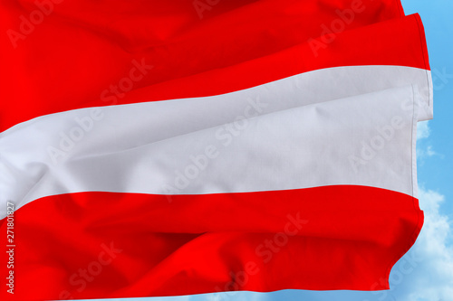 Beautiful silk flag of Austria with soft folds in the wind against a blue sky