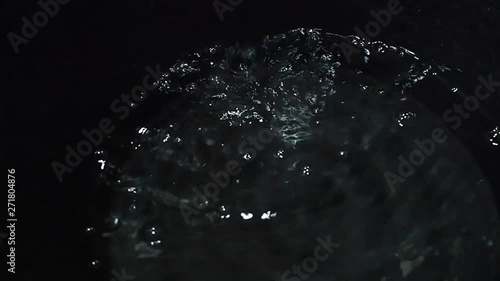 Slow motion drops water in the black container background.