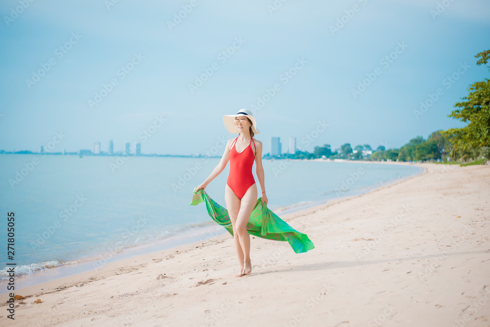 Beautiful woman in red swimsuit is walking on  the beach
