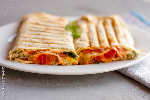 Suluguni in pita bread with greens and tomatoes on a white plate