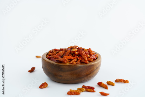 Dried bird's eye chili peppers in a wooden bowl. White background, high resolution