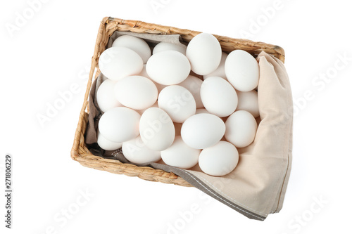 Chicken eggs with kitchen towel in straw basket isolated on white background, top view