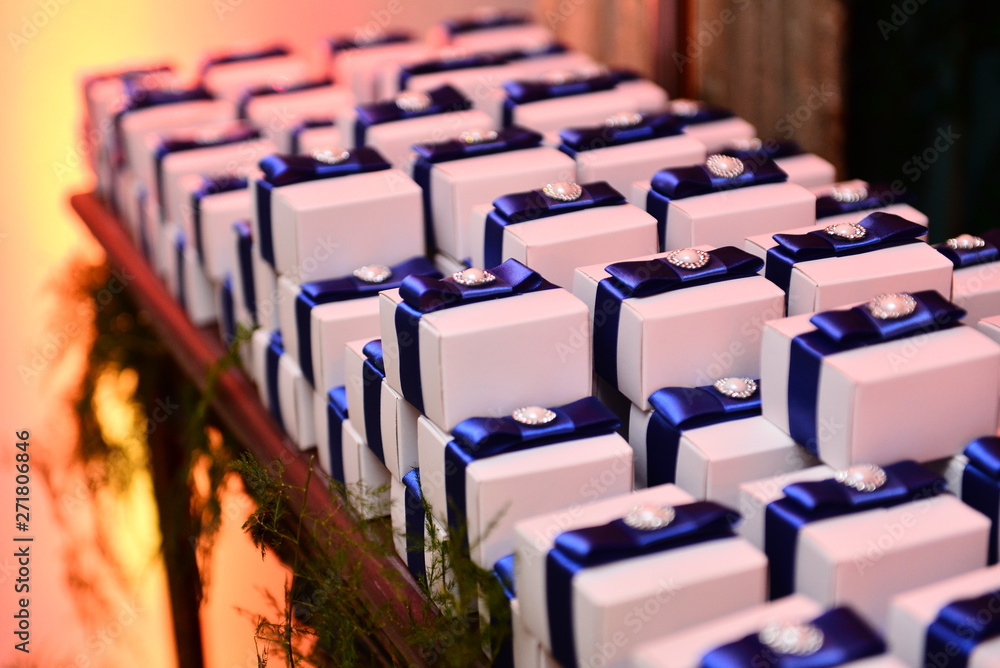 Fototapeta premium happily married in white boxes on candy table in ballroom, candy in the box, party sweets, candy table, blue satin ribbon