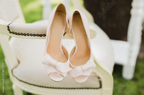 Bridal fashion. Pink shoes and wedding bouquet on a vintage chair.