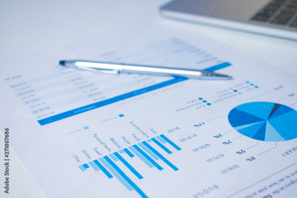 Close-up of a pen on a financial chart on a modern white desk. Close-up of a pen on a financial chart on a modern white desk.