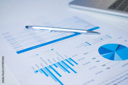 Close-up of a pen on a financial chart on a modern white desk.