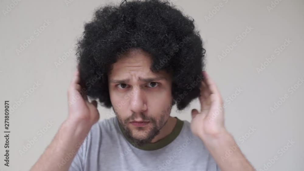 Young curly man looking at the camera and adjusting his hair Young curly man looking at the camera and adjusting his hair
