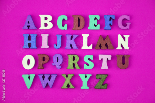 English alphabet made of multi-colored wooden letters on purple background