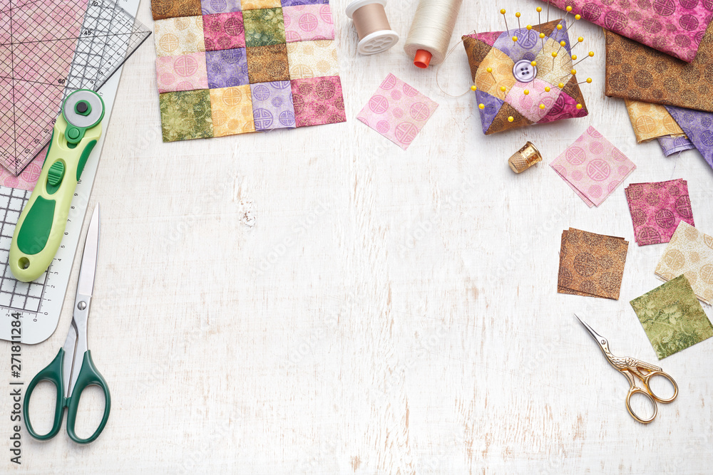 Obraz premium Bright square pieces of fabric, patchwork tools, sewing equipment, traditional quilting
