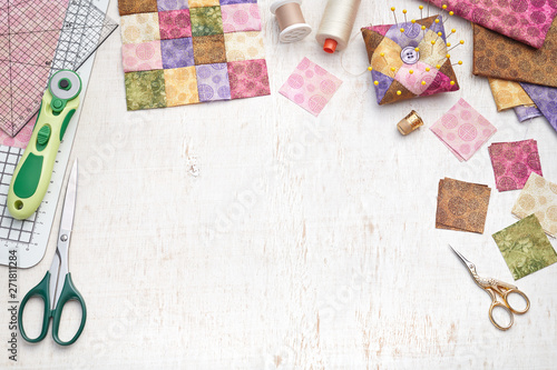 Bright square pieces of fabric, patchwork tools, sewing equipment, traditional quilting photo