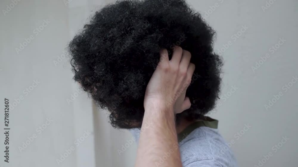 Young man scratching his head and fluffy curly black hair Young man scratching his head and fluffy curly black hair