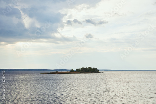 sunny weather with blue clouds on white sky background upon small island with forest