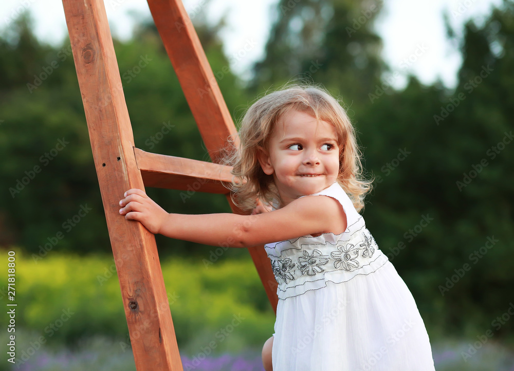 mischievous little girl in a flowered field climbs up the stairs mischievous little girl in a flowered field climbs up the stairs