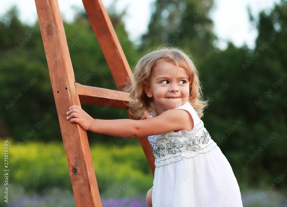mischievous little girl in a flowered field climbs up the stairs mischievous little girl in a flowered field climbs up the stairs