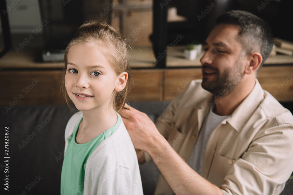 selective focus of smiling father weaving hear of adorable daughter selective focus of smiling father weaving hear of adorable daughter