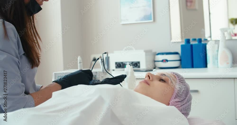 Beautician woman putting on black rubber gloves