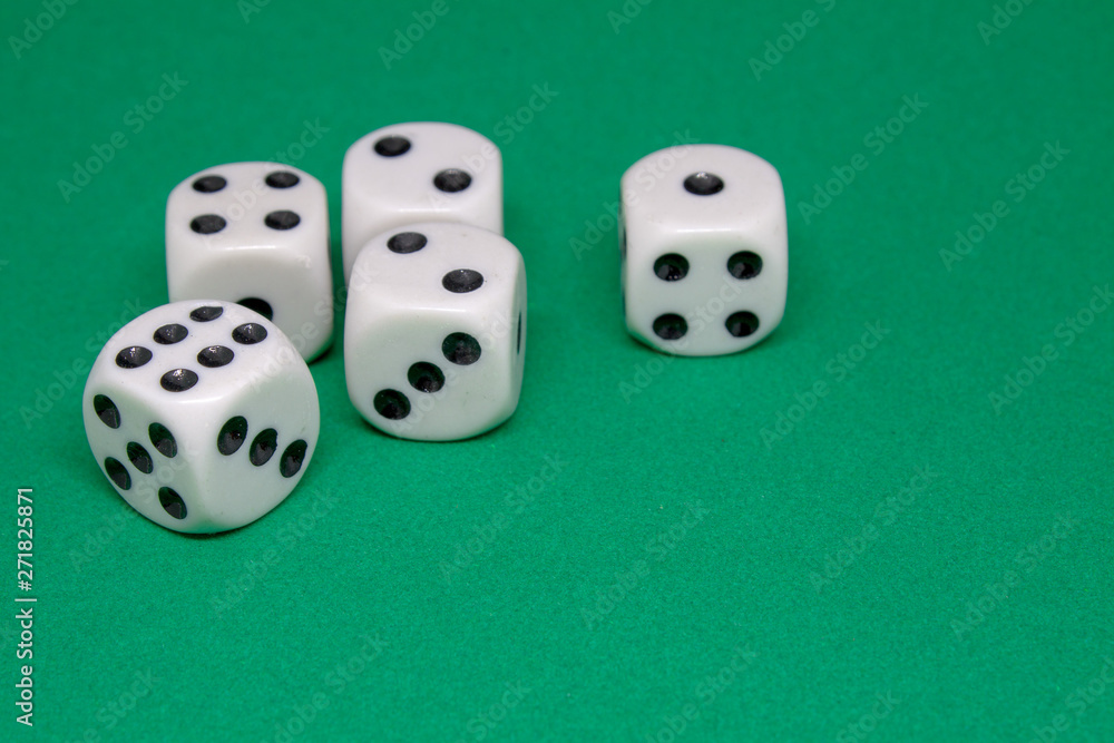Five white playing dice lie in a group on a green playing table close-up Five white playing dice lie in a group on a green playing table close-up