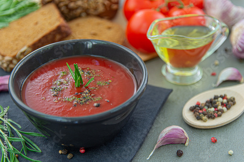 Cold tomato gazpacho soup in a deep plate on a stone background. Traditional Spanish cuisine. The concept of Spanish cold soup of ripe tomatoes.