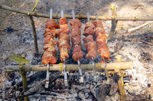 Meat on skewers on fire cooked in nature.