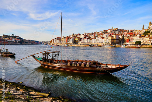 Typowe portugalskie drewniane łodzie, zwane „barcos rabelos”, przewożące beczki z winem na rzece Douro z widokiem na Villa Nova de Gaia w Porto, Portugalia